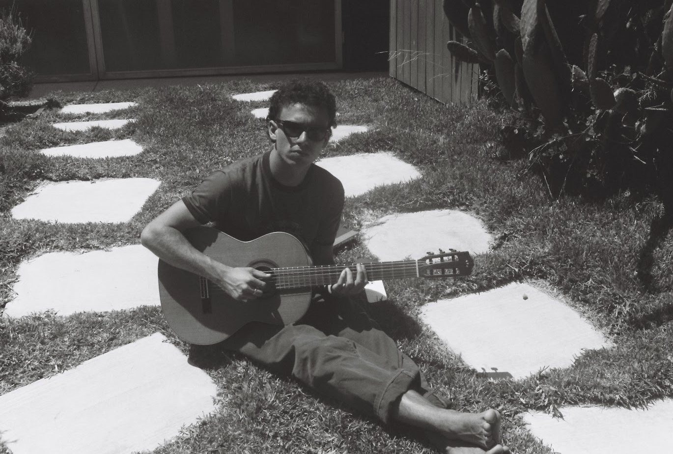 G La Londe V sitting on stepping stones playing a classical guitar