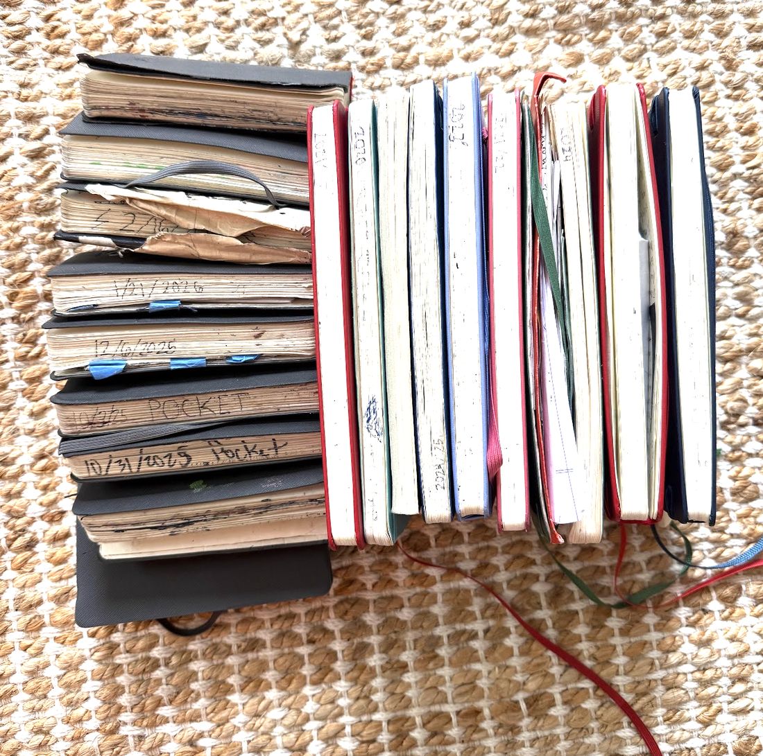 Two stacks of well-used notebooks, dated on their page edges