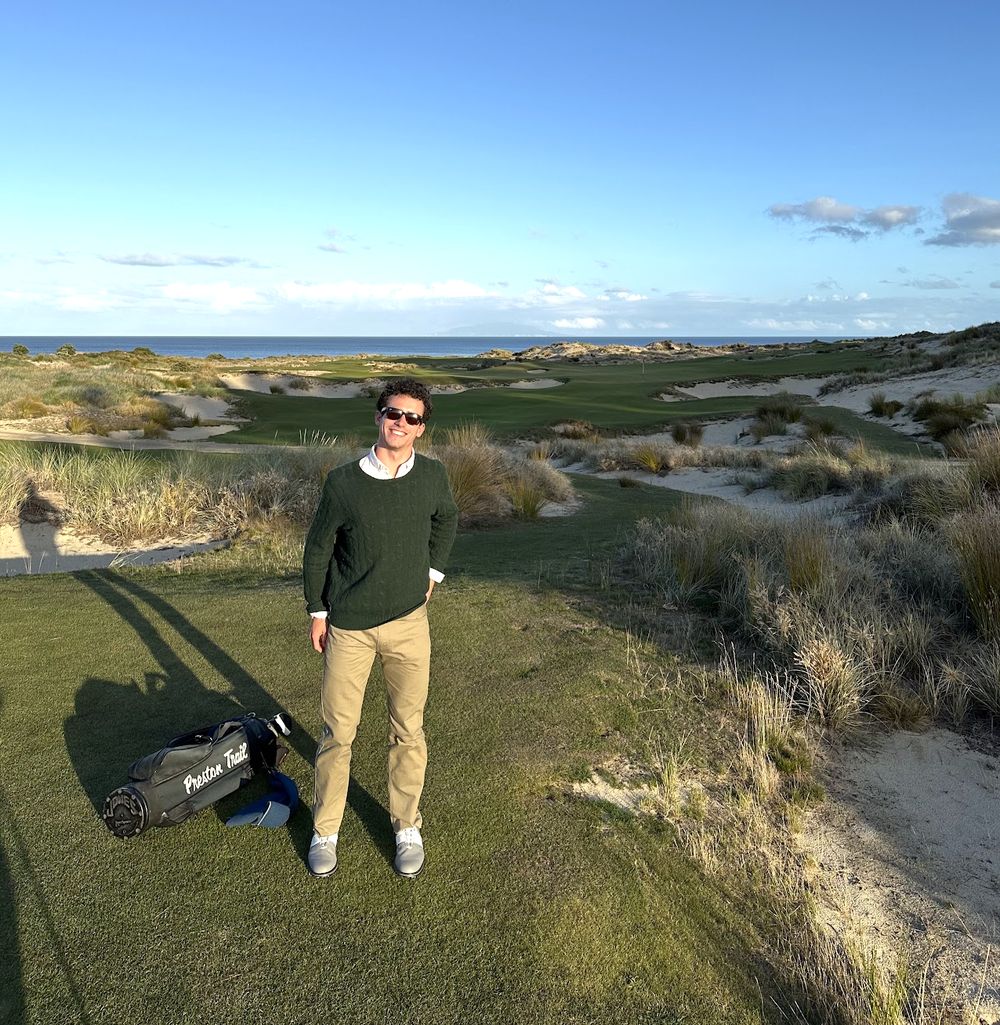 G standing on a links golf tee among dunes and marram grass with the ocean behind